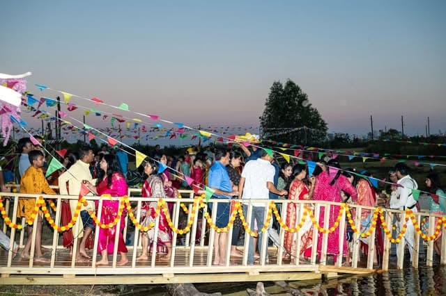 Families crossing the marigold-draped walkway to the water at dusk