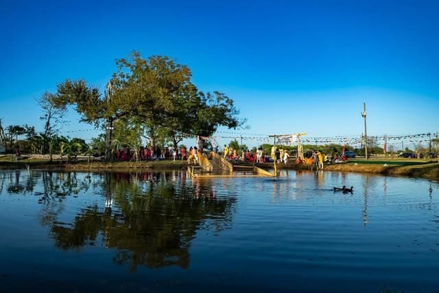 Morning light over the pond with devotees on the ghat under festival buntings